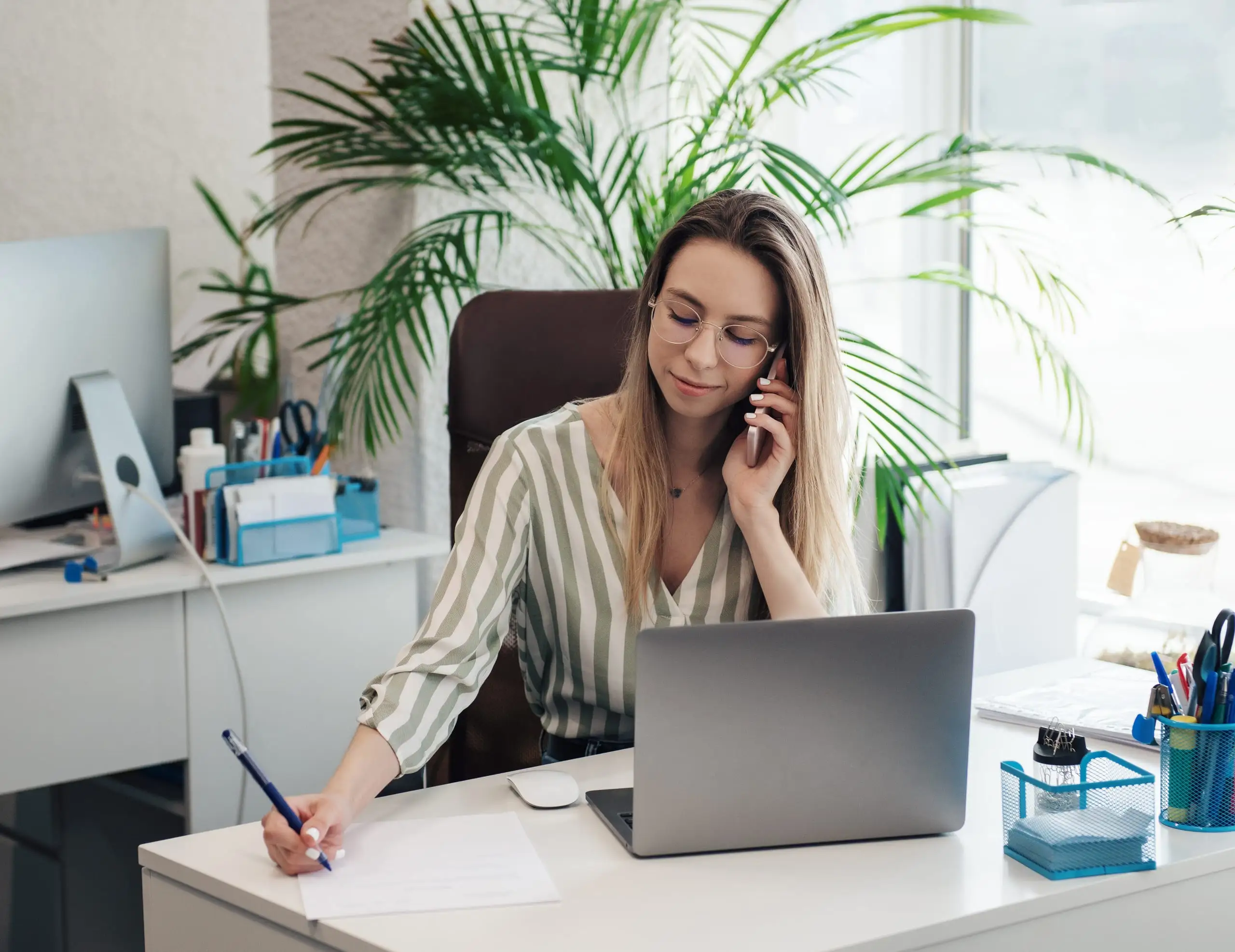 Sprachlehrerin am Schreibtisch – telefonierend und Notizen machend